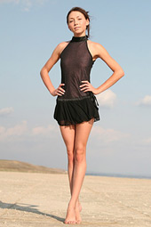 Tall skinny brunette taking off her transparent black dress on the beach