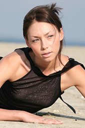 Tall skinny brunette taking off her transparent black dress on the beach