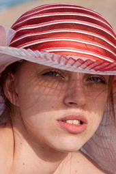 Arina wears a wide-brimmed hat while out nude sunbathing